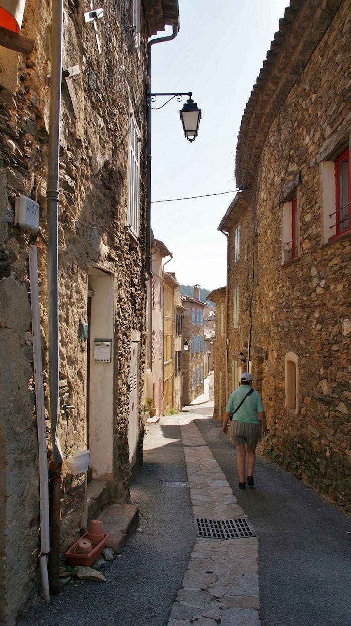 stats-img A person walking down a sunlit historic alleyway with rustic stone walls.